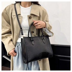 Dettaglio borsa tote nera con trama a coccodrillo indossata con trench beige