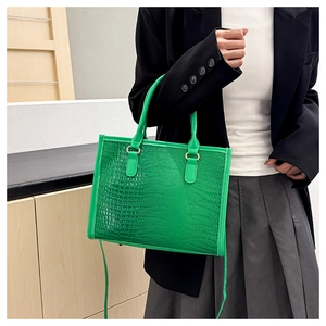 Dettaglio della borsa tote verde brillante con stampa coccodrillo indossata dalla modella
