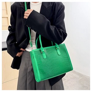 Dettaglio borsa tote verde con stampa coccodrillo, anelli dorati e tracolla sottile