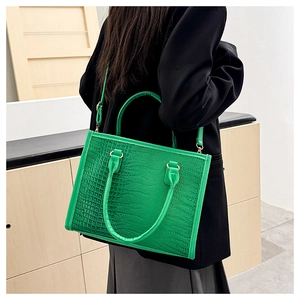 Borsa tote verde con motivo a coccodrillo indossata da una modella in abito nero