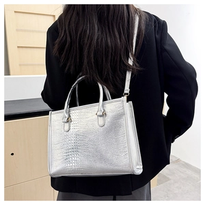 Borsa tote argento con trama a coccodrillo mostrata su modella per scala dimensionale