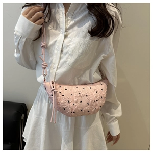 Detail of pink crescent bag featuring black bow patterns and knotted shoulder strap