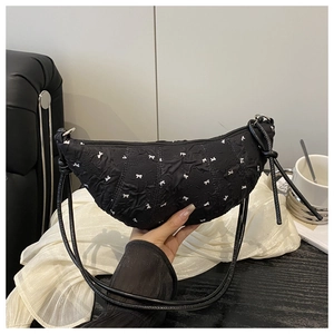 Close-up of black crescent underarm bag with white bow pattern and pleated fabric detail