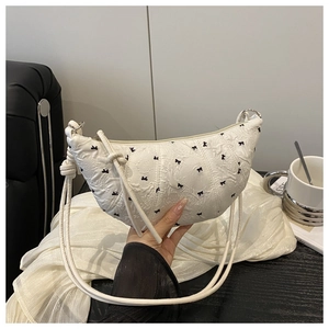 Detail of white crescent bag with black bow embroidery and knotted shoulder strap