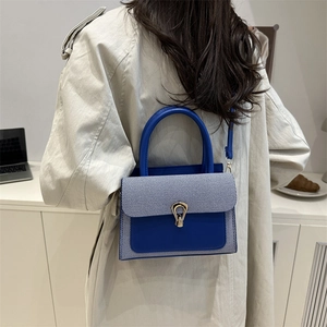 Blue faux leather crossbody bag with striped flap and gold horseshoe buckle closure