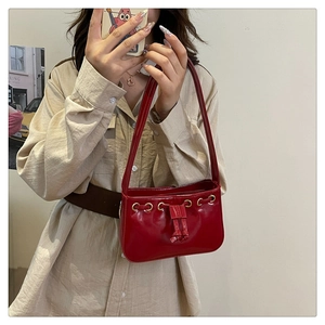 Detail of red glossy shoulder bag with unique drawstring and gold metal ring accents