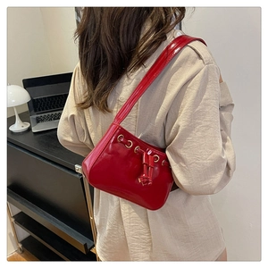 Detail of red patent leather shoulder bag with decorative drawstring and gold metal eyelets