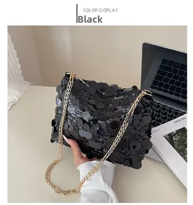 Detail of black sequin shoulder bag with golden chain strap and textured shimmer
