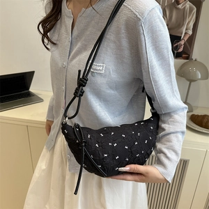 Minimalist black crescent bag with white bow pattern and stylish knotted shoulder strap