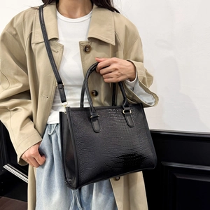 Borsa tote nera con motivo a coccodrillo e dettagli dorati indossata da modella