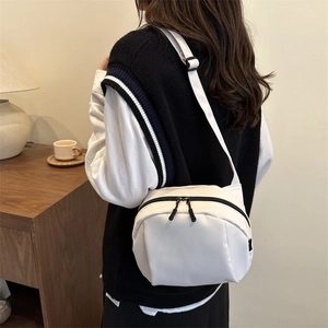 Minimalistische weiße Nylon-Umhängetasche mit verstellbarem Gurt in gemütlichem Interieur