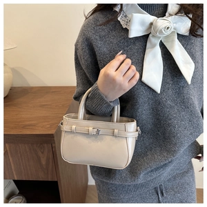 Close-up of a chic cream PU leather handbag with metal buckle and fixed handles