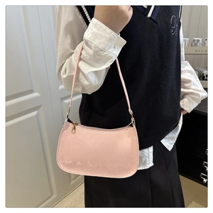 Pink baguette bag with snake texture embossing and gold zipper shown on shoulder