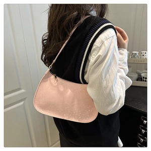 Detail of pink faux crocodile embossed baguette bag worn by model in a home setting