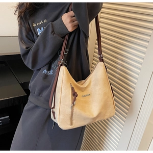 Detail view of large beige suede shoulder bag with vertical zipper and leather straps
