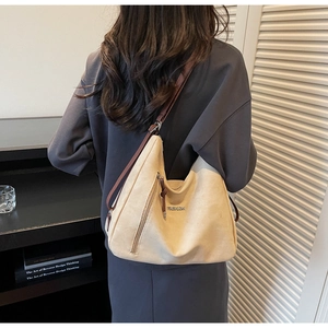 Detail of a large beige tote bag on model showing soft texture and brown straps