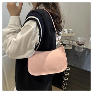 Détail du sac baguette rose clair montrant la texture animale et la forme en demi-lune