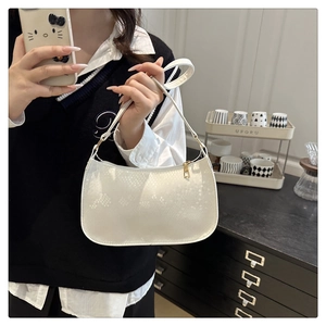 Close-up of white crescent bag with snakeskin texture and gold zipper detail