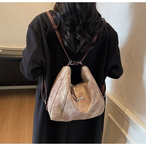 Detail of vintage brown suede hobo backpack with vertical metal zipper and leather strap
