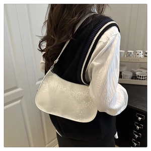 Vue détaillée d'un sac hobo blanc texturé porté à l'épaule dans un décor de style de vie