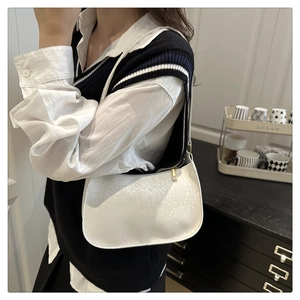 Détail du sac baguette blanc avec texture en similicuir et fermeture éclair dorée élégante
