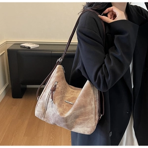 Close-up of brown suede tote bag featuring decorative zipper and metallic fashion logo
