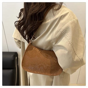 Detailed view of a brown faux-snake skin hobo bag with sleek shoulder strap on a model