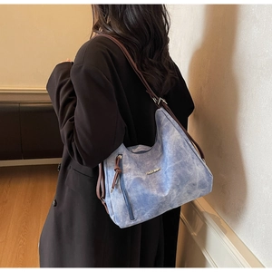 Detail of blue marble-textured tote bag with adjustable brown strap on model