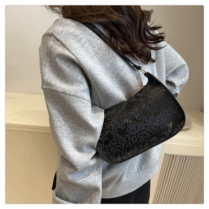 Detail of black snake-textured hobo bag showing the elegant shoulder wear and material