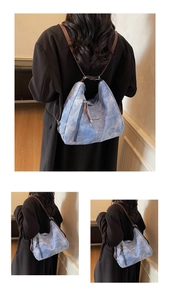 Detail of the vintage washed blue multi-purpose backpack with brown straps on model