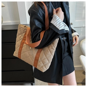 Detail of quilted tote bag featuring khaki nylon fabric and orange contrast shoulder straps