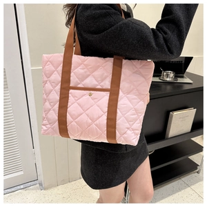 Detail of pink quilted tote bag showing diamond stitching and front pocket on shoulder