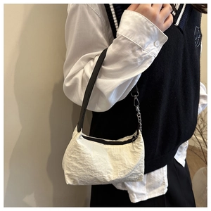 Detail of white textured nylon shoulder bag with black strap and metal chain accent