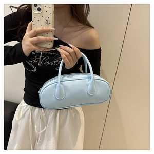 Close-up of a light blue patent leather bowling bag held by a stylish model