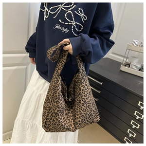 Detail shot of a large leopard print tote bag being carried in a stylish indoor setting