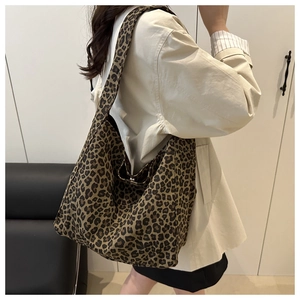 Macro view of leopard print canvas hobo bag showing texture and wide shoulder strap