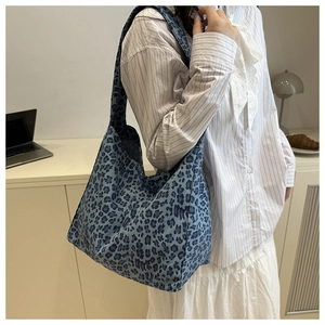 Blue leopard print canvas hobo bag worn by model in a cozy indoor lifestyle setting
