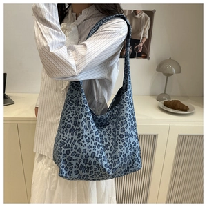 Detailed texture of blue leopard print hobo bag worn by a model in a minimalist room