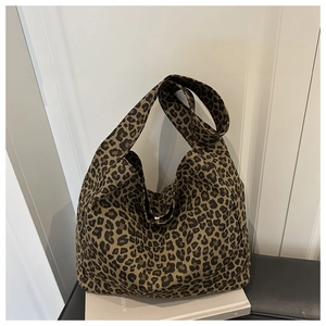 Close-up of leopard print canvas tote bag placed on a book and black leather bench