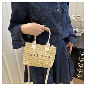 Détail du sac cabas tissé beige clair avec broderie et poignées en cuir crème