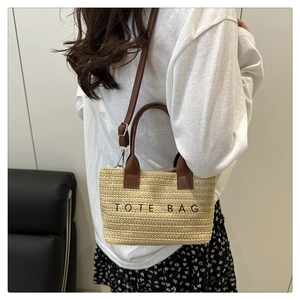 Detail of straw tote bag with brown leather handles and Tote Bag embroidery for beach vacations
