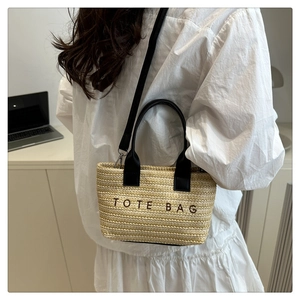 Détail d'un sac cabas en paille avec broderie TOTE BAG noire et bandoulière réglable