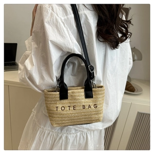 Détail du sac cabas en paille tissée avec anses en cuir noir et broderie élégante