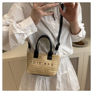 Selfie miroir montrant un cabas en paille beige avec poignées noires et broderie TOTE BAG