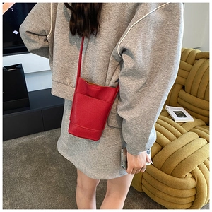 Red lychee pattern leather crossbody bucket bag shown on a model in a cozy setting