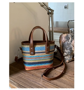 Détail du sac tissé coloré avec poignées en cuir marron et accents de rivets métalliques