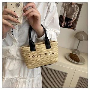 Détail d'un mini sac cabas en paille avec broderie noire tenu par un mannequin