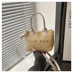 Détail d'un sac cabas en paille tressée avec broderie marron et bandoulière en cuir élégante