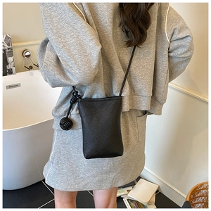 Rear view of model wearing a black litchi pattern mini crossbody phone bag with knot detail