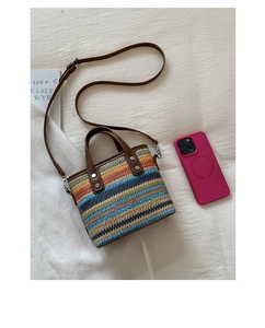 Détail d'un sac seau en paille à rayures arc-en-ciel avec anses en cuir marron et boucles